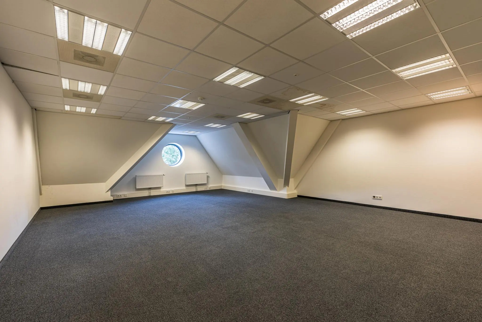 Leeg kantoor met schuin dak en rond raam aan de Laan Blusse van Oud Alblas.